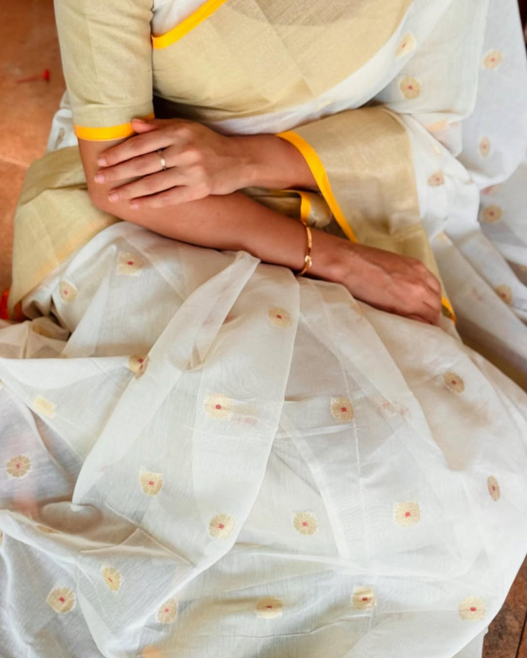 Close-up of a person wearing a light-colored saree with floral patterns.