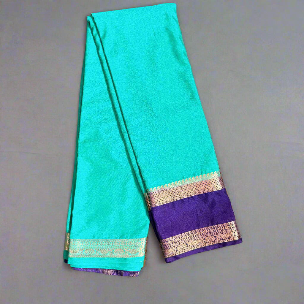 Teal saree with purple border on a gray surface