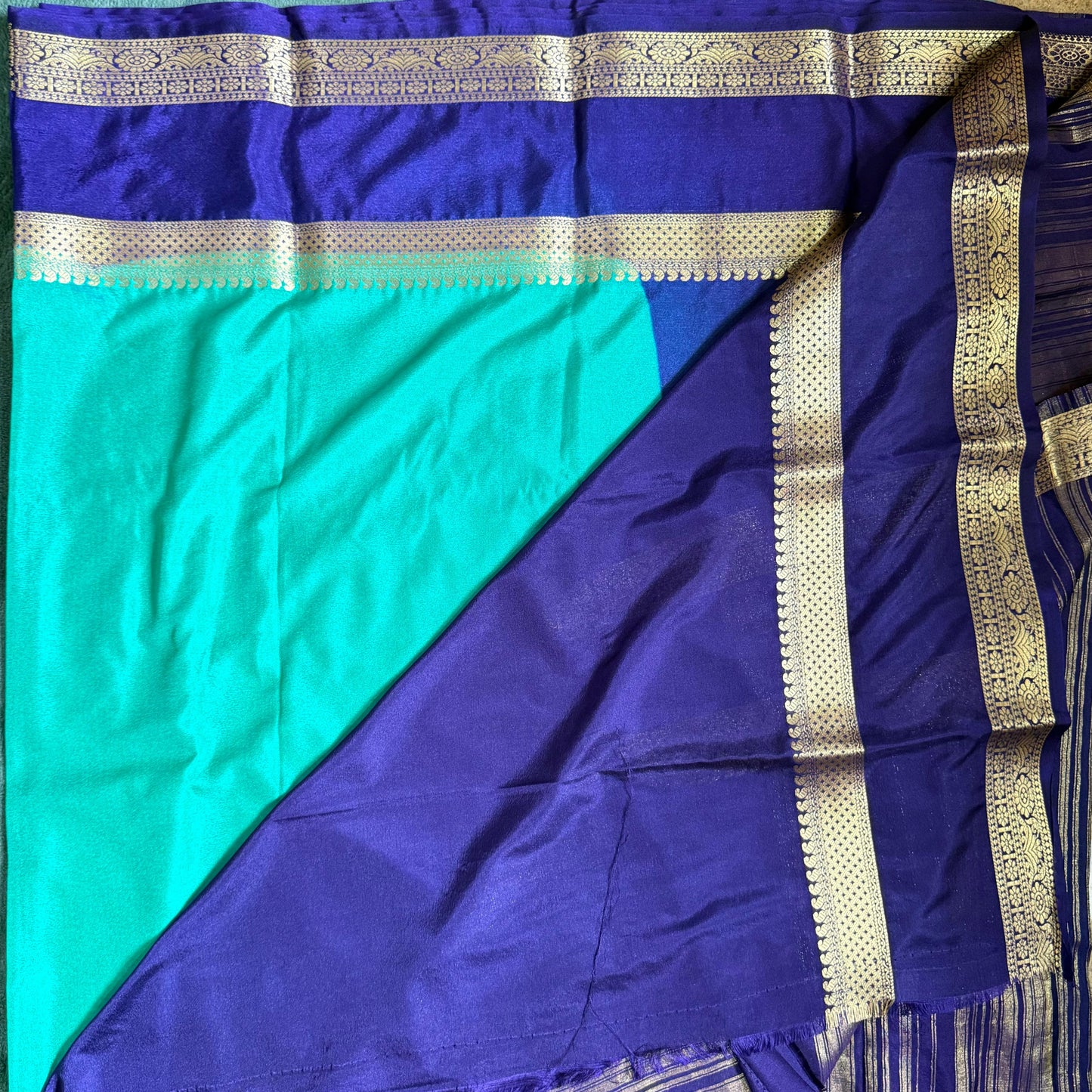 Blue and green saree with gold border on a flat surface