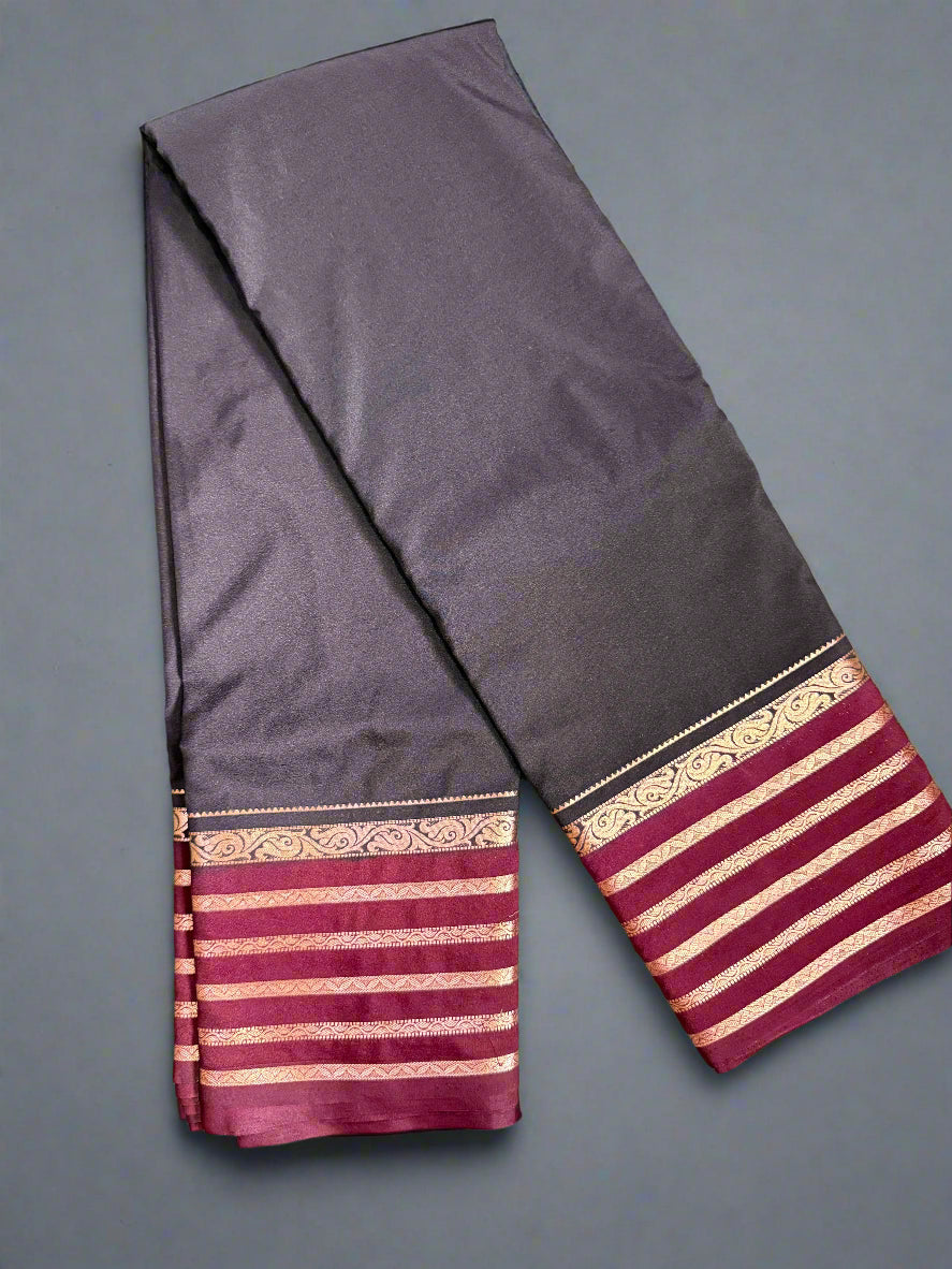 black saree with gold and red border on a textured surface