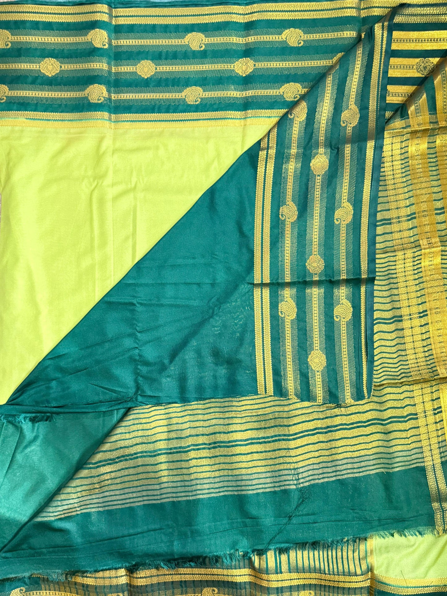 Green and yellow saree with intricate patterns on a neutral background