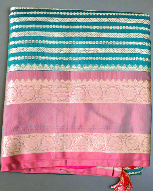 A folded Soft Litchi Silk Saree with jacquard work, displayed on a grassy surface, with a mix of green, pink, and metallic silver colors visible.