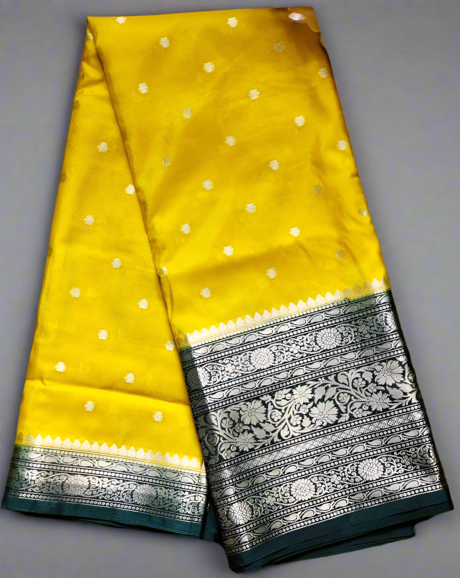 Yellow saree with white dot pattern and black border on a gray background
