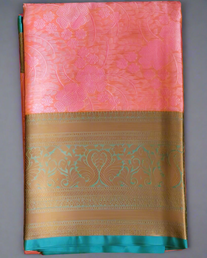 Folded pink Banaras Kora Muslin saree with intricate geometric patterns and Zari weave detailing on the pallu and blouse, displayed on a green background.