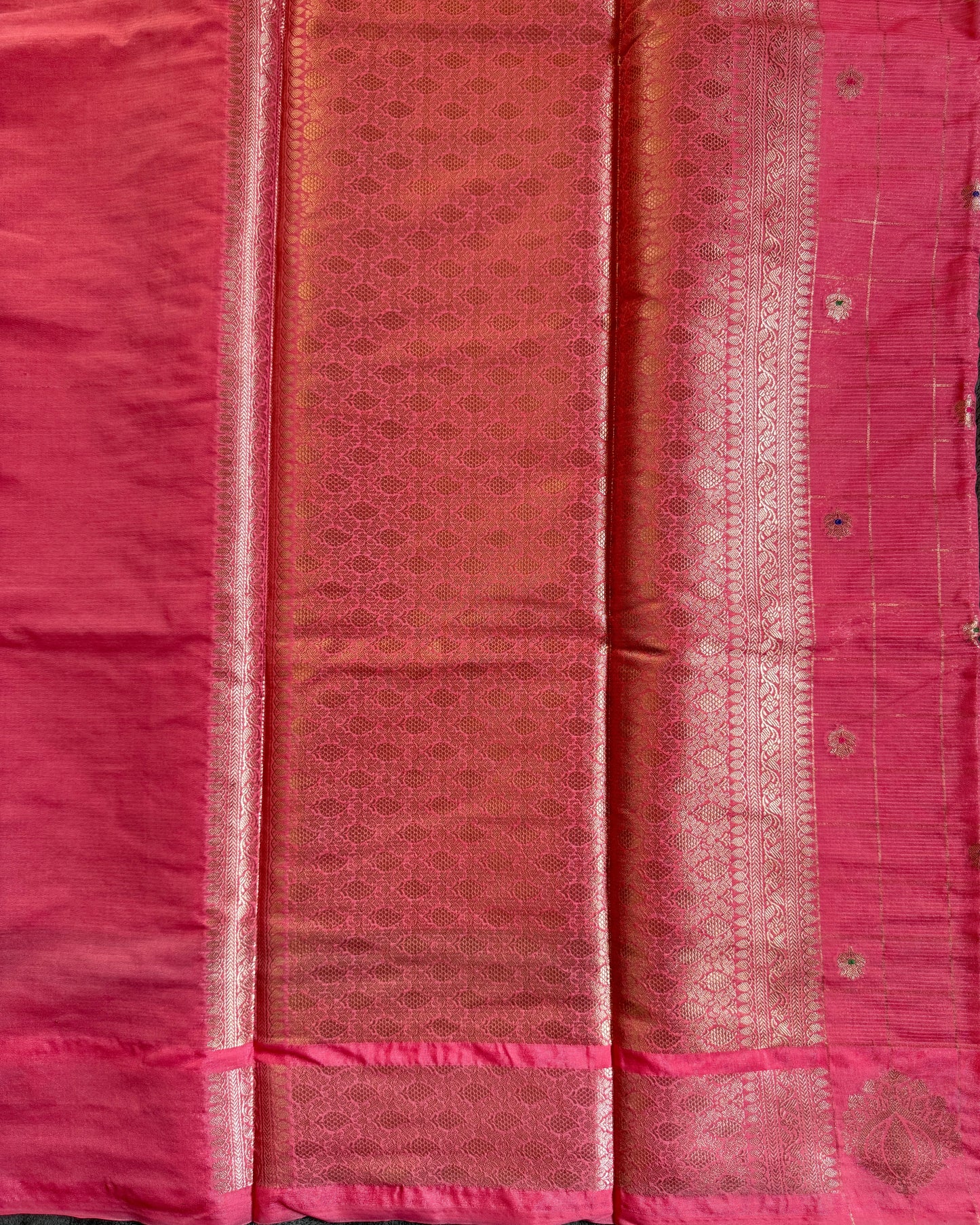 Pink fabric with intricate patterns and embroidery on a dark background