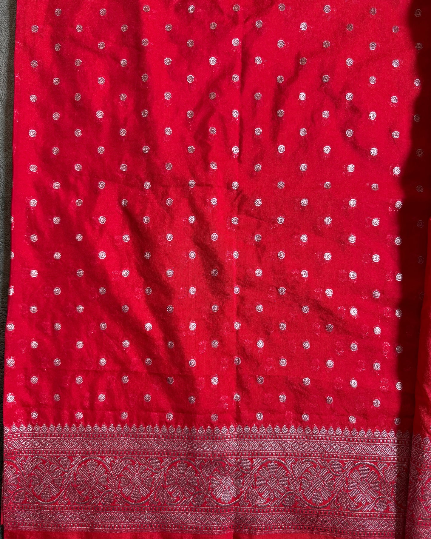 Red fabric with white patterns and a decorative border