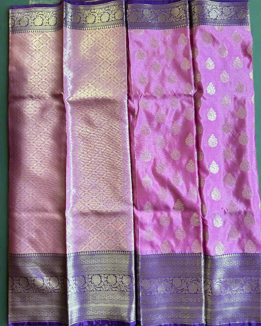 Pink and purple saree with intricate patterns on a green surface