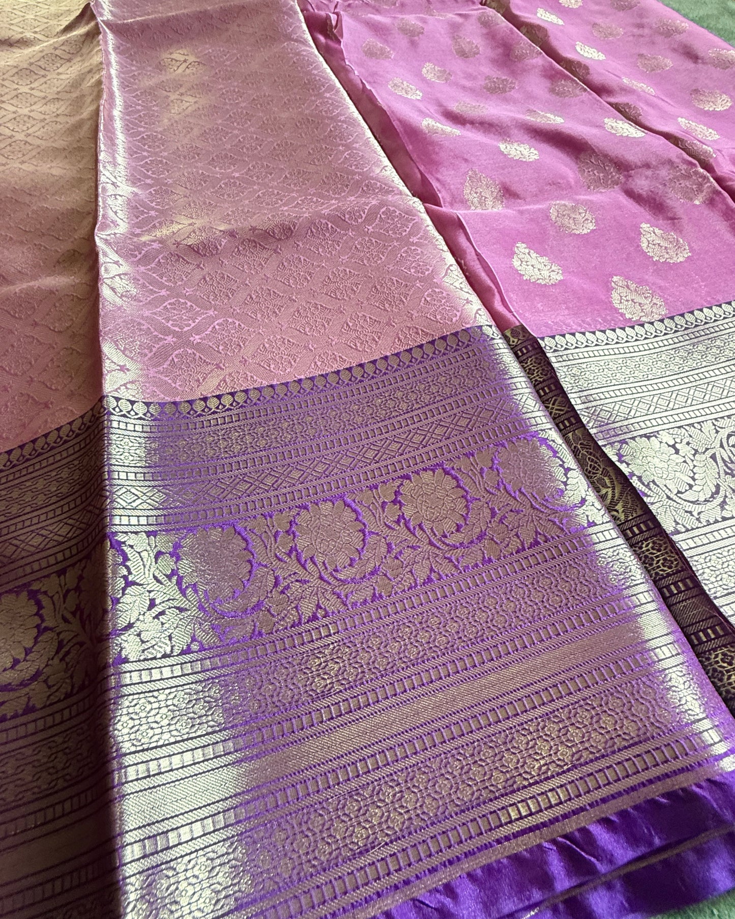 Purple and pink saree with intricate patterns on a fabric surface