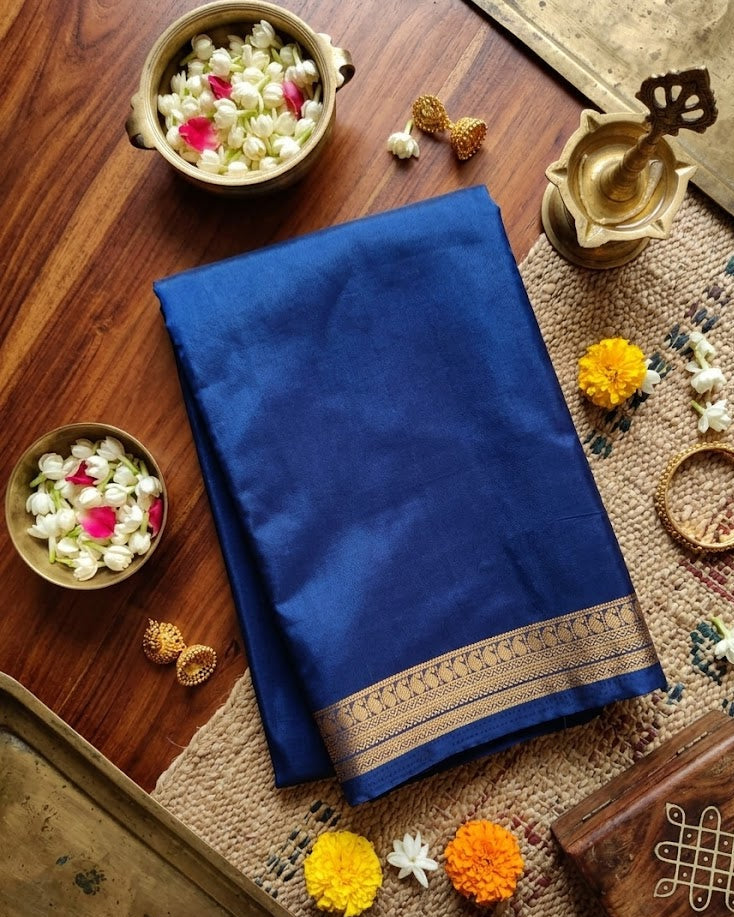 Blue saree with gold border on a wooden table with decorative items