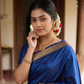 Woman in a blue saree with gold details in an indoor setting
