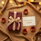 Gift box with a bow, candles, and a card on a textured surface with bokeh lights