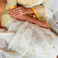 Close-up of a person wearing a light-colored saree with floral patterns.
