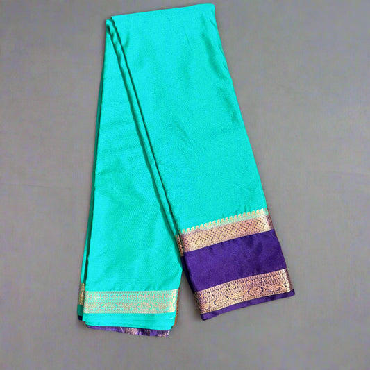 Teal saree with purple border on a gray surface