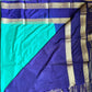 Blue and green saree with gold border on a flat surface