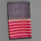 Black saree with red and gold border on a textured gray background