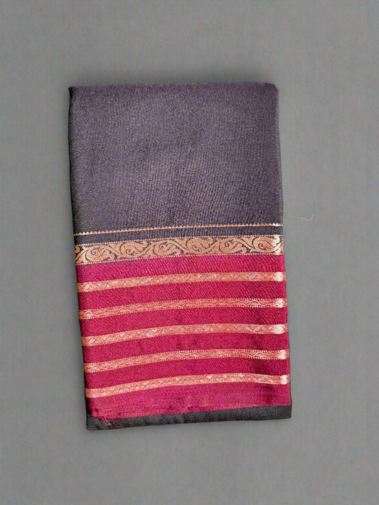 Black saree with red and gold border on a textured gray background