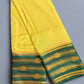 Yellow saree with green and gold border on a gray background