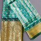 Green saree with gold border and patterns on a gray background