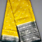 Yellow saree with white dot pattern and black border on a gray background