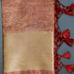 A folded maroon and beige banarasi handwoven crush tissue silk saree with zari weave pallu and blouse, displayed on a green background.