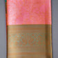 Folded pink Banaras Kora Muslin saree with intricate geometric patterns and Zari weave detailing on the pallu and blouse, displayed on a green background.