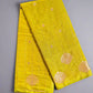 Yellow fabric with gold floral patterns on a gray surface