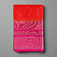 Red and pink saree with a textured pattern on a gray surface