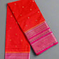 Red saree with pink border on a textured gray background
