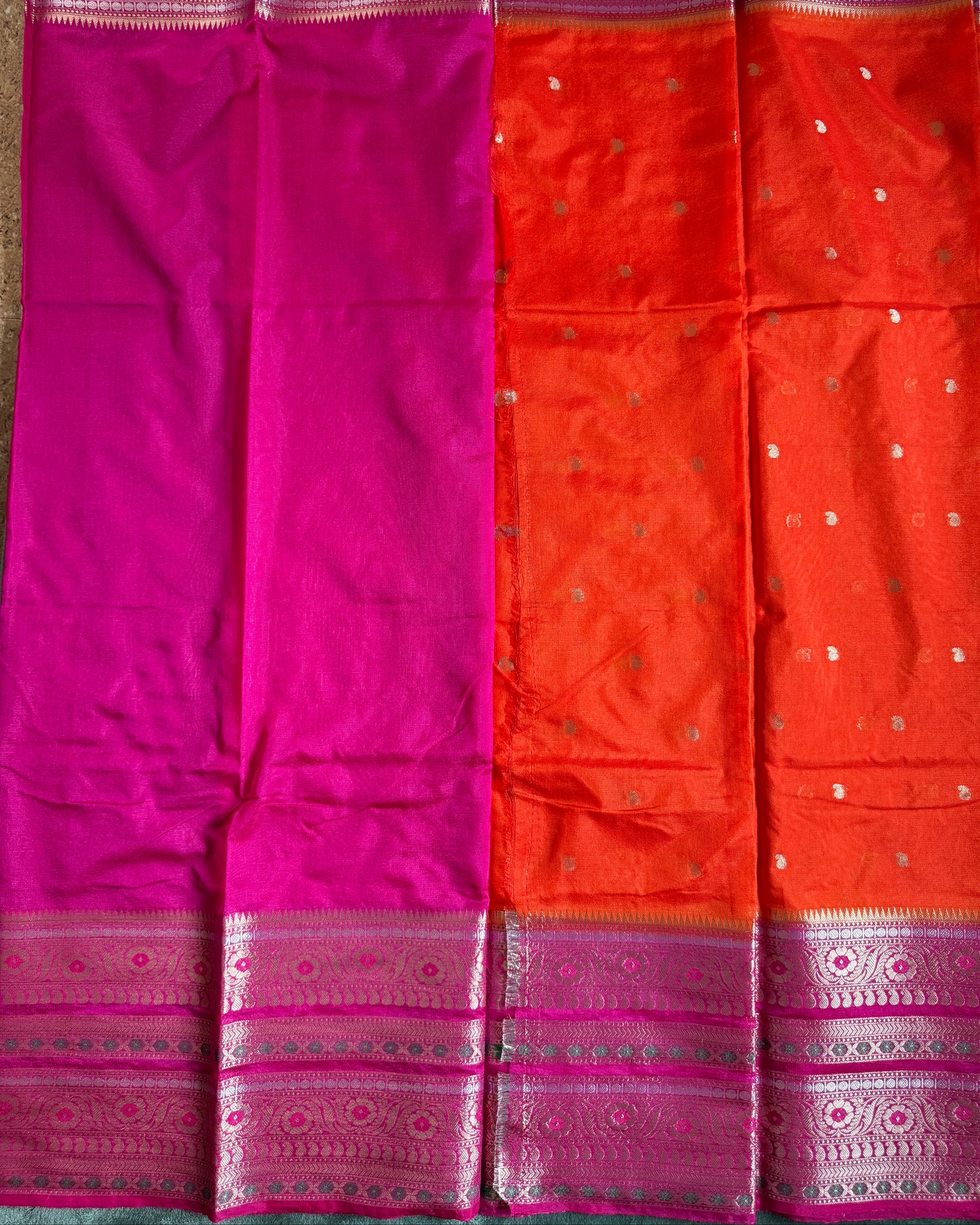 Saree with orange and pink fabric and decorative border on a gray background