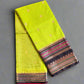 Folded fabric with a green base and patterned border on a textured gray surface
