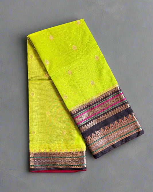Folded fabric with a green base and patterned border on a textured gray surface