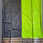 Green and black saree with decorative borders on a textured surface