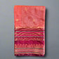 Folded fabric with pink and red patterns on a gray surface