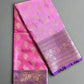 Pink saree with gold patterns and a purple border on a textured gray background