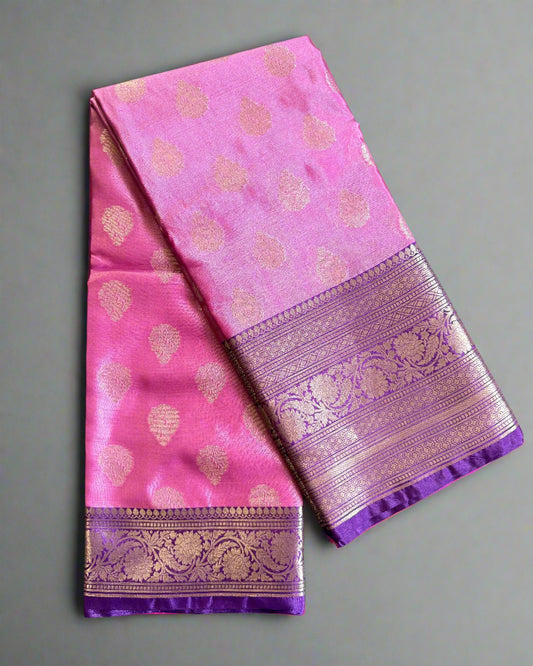 Pink saree with gold patterns and a purple border on a textured gray background