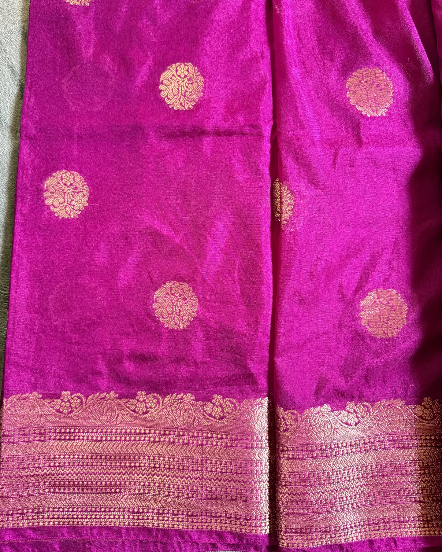 Purple fabric with gold circular patterns and a border on a textured surface