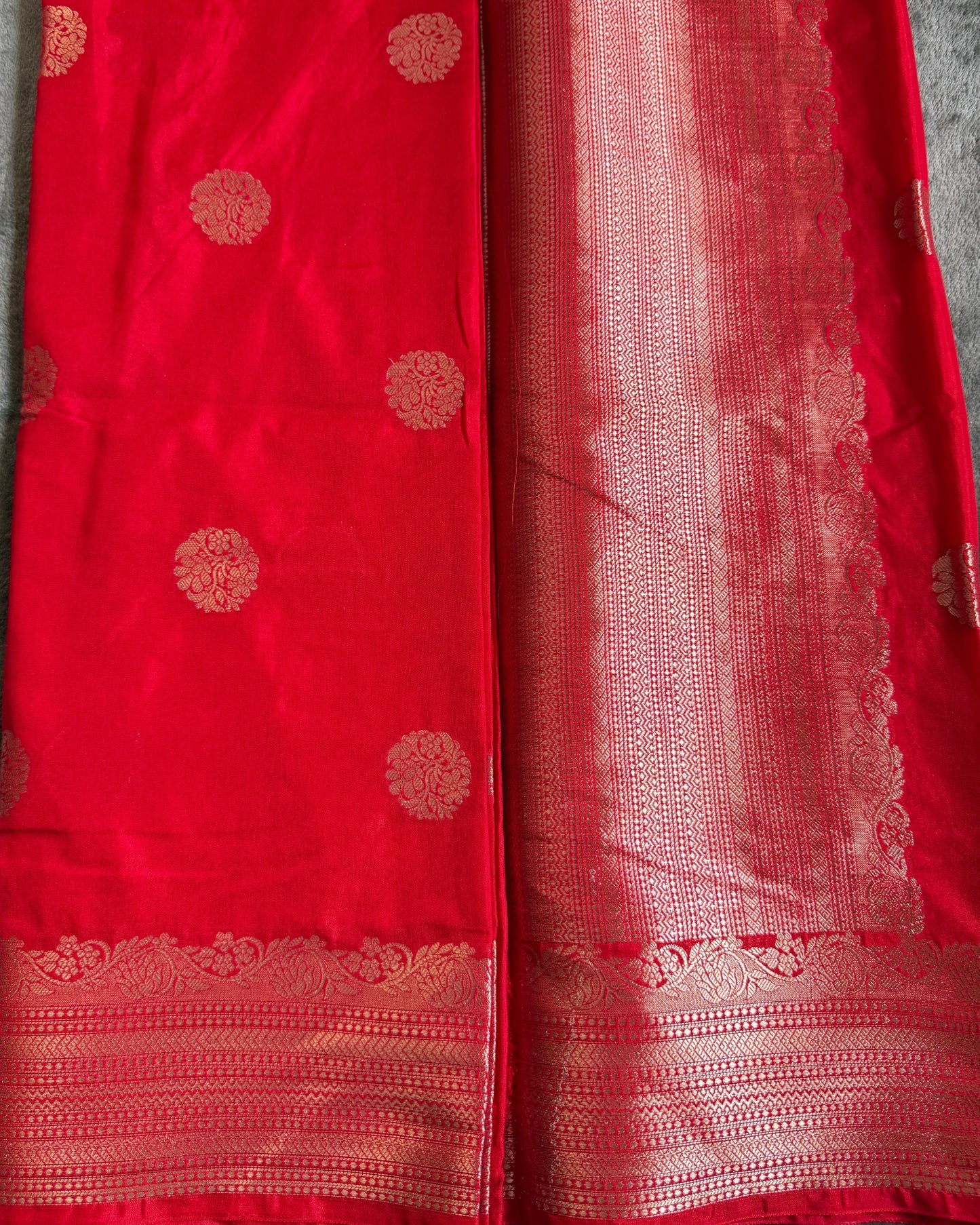 Red fabric with gold patterns on a gray surface