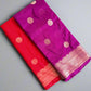 Two sarees, one purple and one red, with gold patterns on a gray surface.