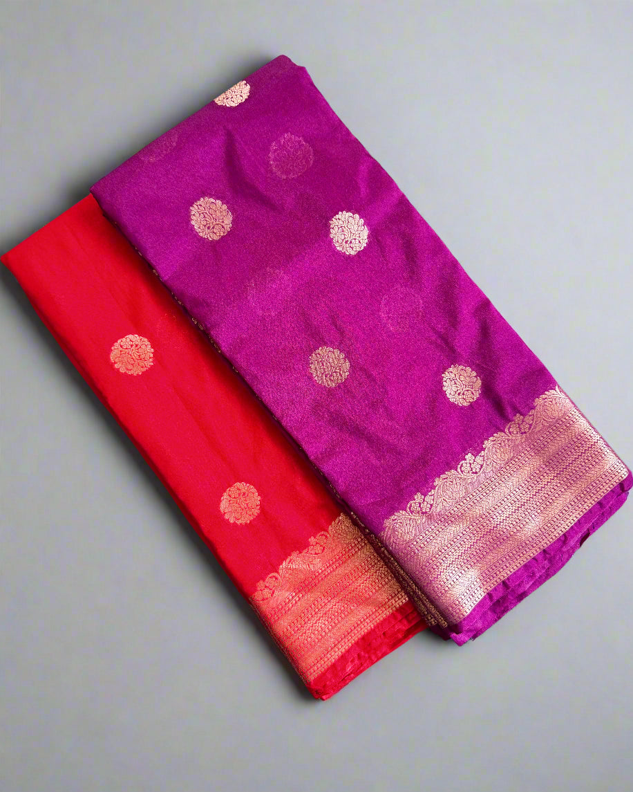 Two sarees, one purple and one red, with gold patterns on a gray surface.