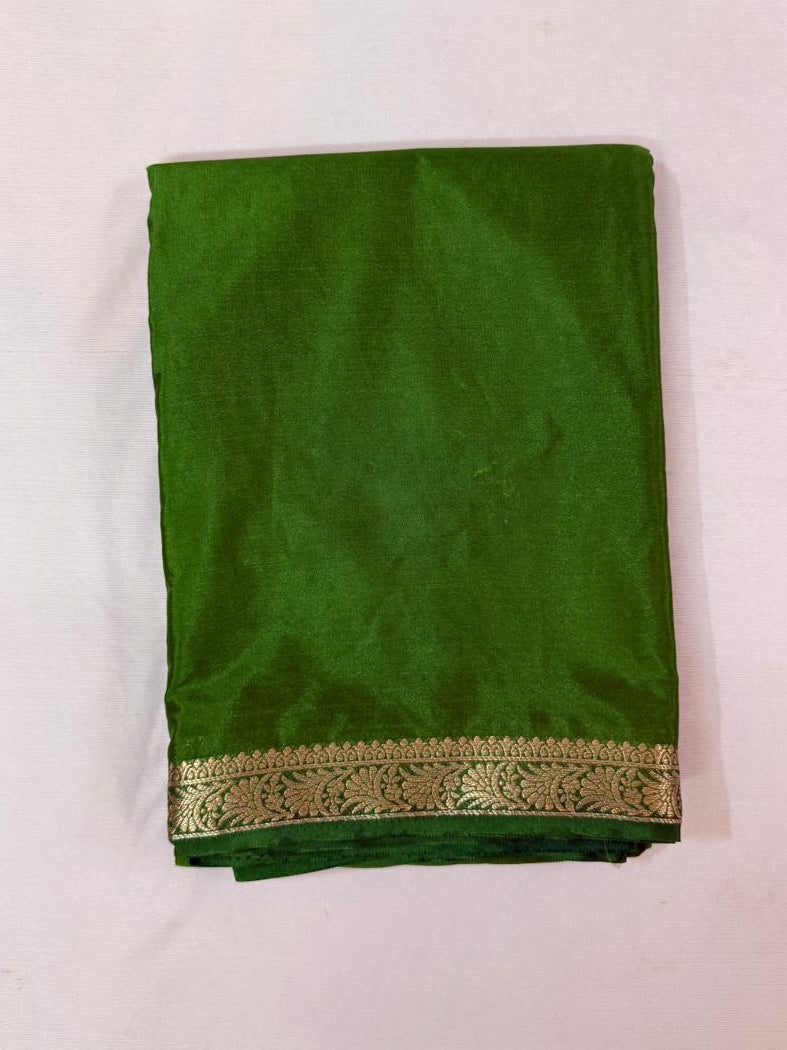 Green saree with a gold border on a white background