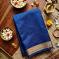 Blue saree with gold border on a wooden table with decorative items