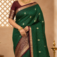 Woman wearing a green saree with gold border indoors