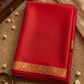 Red saree with gold border on a textured surface