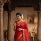 Woman in a red saree standing in a temple setting
